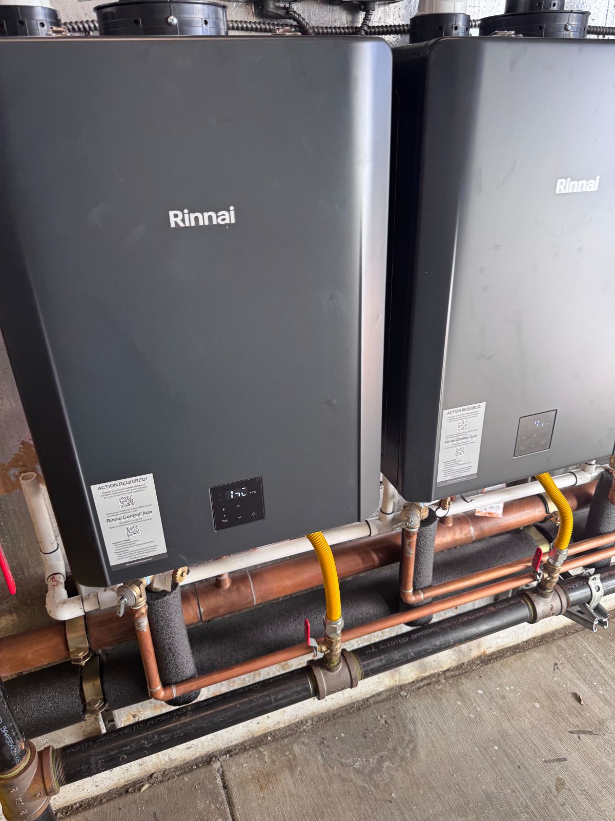 Two commercial Rinnai tankless units piped together on a wall